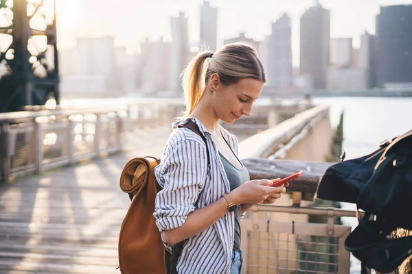 スマートフォンアプリでGpsを追跡し 大都市周辺のオンラインガイドを検索しながら 旅行バックパックを持つ白人女性観光客のサイドビュー ニューヨーク — ストック写真