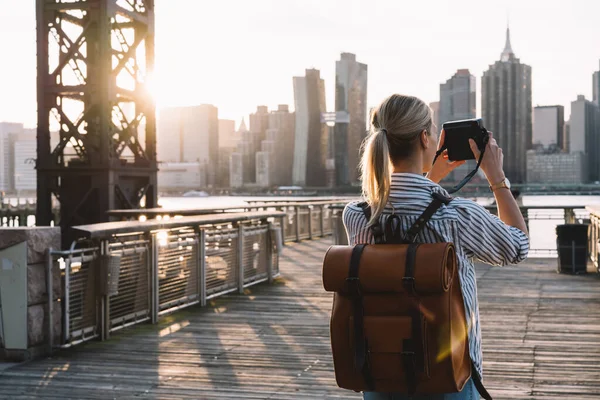 アメリカの都会の風景をバックパックで旅するスタイリッシュな女性観光客の風景やレトロなインスタントカメラを使用してマンハッタンのランドマークの写真をクリックして 写真趣味の概念 — ストック写真