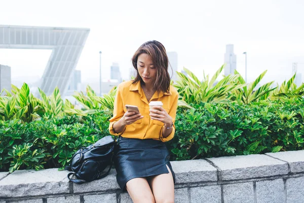 Skupiona Nowoczesna Azjatka Luźnych Ubraniach Plecakiem Pijąca Kawę Używająca Smartfona — Zdjęcie stockowe