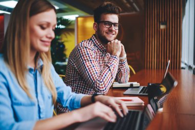 Neşeli, optik göz giyimi uzmanı, dizüstü bilgisayarda çalışan bayan iş arkadaşının yanında oturan mutlu iş arkadaşları, dijital piyasada yeni aletler ve sunumlarla ilgili projelerini tamamlıyorlar.