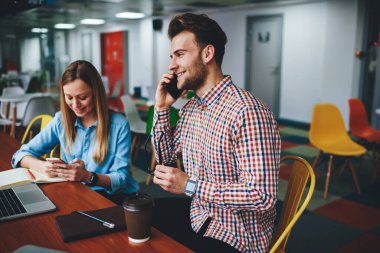 İki genç, kafeteryada akıllı telefonlar kullanarak oturuyor, kadın internet blogcusu, iş vereniyle cep telefonunda konuşan serbest çalışan erkek blogcu, metin yazımında üretkenliği arttırıyor.