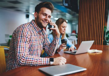 Cep telefonlu genç bir adam dizüstü bilgisayarında yazan bir sonraki kadın, mutlu bir erkek öğrenci akıllı telefondan e-öğrenim süresince kablosuz internet yeni mobil cihaz uygulamalarını anlatıyor.