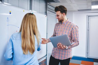 Günümüz ofislerinde iş birliği hakkında konuşan sıradan giyinmiş erkek ve kadın netbook, beyaz yönetim kurulundan gelen bilgiyi analiz eden beyaz erkek ve kadın ekonomistler