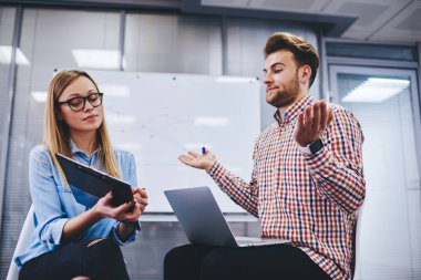 Optik gözlük takan zeki bayan öğretmen, üniversite ödevi için bilgi, strateji oluşturma ve analiz etme konusunda işbirliği yapan kafası karışmış erkek öğrenciye özel ders veriyor.