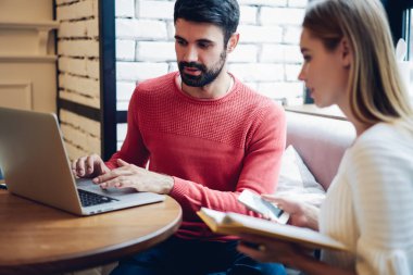 Başlangıç projesinde işbirliği yapan Kafkas erkek ve kadın serbest çalışanlar modern dizüstü bilgisayarda 4G kablosuz internete bağlı bilgilendirici web sitesinde yararlı bilgiler okuyorlar