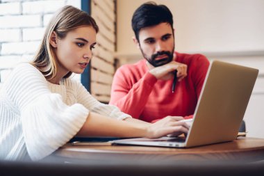 Erkek ve kadın partnerler, modern dizüstü bilgisayarda uygulamalar üzerinden ders programı izleyerek uzak mesafelere çalışmak için kablosuz internet bağlantısı ve yetenekli programcıların işbirliği kullanıyor.