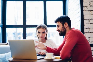 Erkek ve kadın serbest çalışanlar, web sitesinde bilgi okurken ortak projenin detaylarını tartışarak, program kodları üzerinde uzaktan beyin fırtınası yaparak çalışan yetenekli bilişim uzmanları.