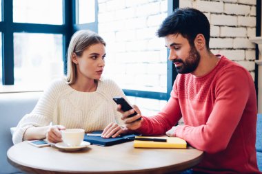 Millennial hipster çalışanları seyahat sitesindeki bilgileri analiz edip modern cep telefonu cihazıyla internet üzerinden otel rezervasyonu yapıyorlar.