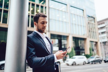 Kafkas erkek girişimci cep telefonu aygıtı ile e-posta bildirimi kontrol finans bölgesinde durmakta, akıllı iş adamı cep telefonuyla ağ kurmak için 4G kablosuz kullanıyor