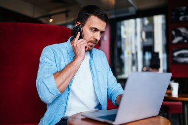 Gelişigüzel giyinen yetenekli bir adam bilgisayar güncelleme sistemi hakkında danışmanlık için çevrimiçi müşteri hizmetlerini arıyor, erkek programcı uygulamayla telefon ederken veri bilgilerini başlatıyor