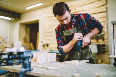 Genç profesyonel erkek marangoz, kendi dekoratif inşaatını yapmak için ahşap döşeme yapıyor. Kendi garajındaki iş süreçlerine yoğunlaşıyor, atölyede gelişim kavramı var.
