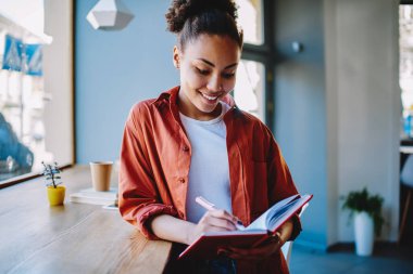 Üniversite kampüsündeki meslektaşlarıyla bilgi organizasyonu planlarken gülümseyen kadın, boş zamanlarında ders kitabında ilginç zihinlere dikkat çekiyor.
