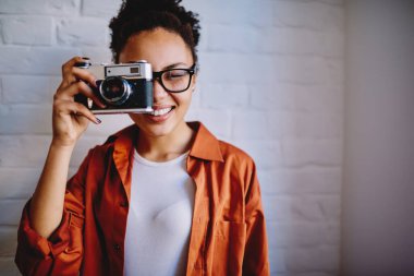 Neşeli Afrikalı kadın fotoğrafçının yarım boy portresi boş zamanlarında geçmişe dönük fotoğraf makinesiyle fotoğraf çekiyor, koyu tenli amatör favori hobi için klasik ekipmanlarla zaman harcıyor.