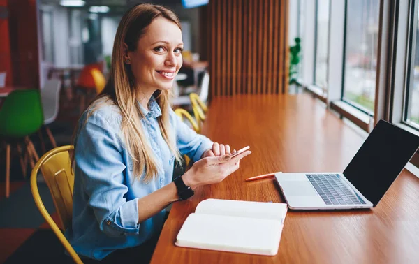 Joven Mujer Positiva Sonriendo Modestamente Cámara Sentada Mesa Madera Con — Foto de Stock