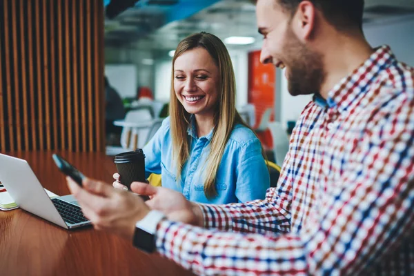 Modern teknolojileri kullanan bir çift gülen beyaz genç, akıllı telefona yeni uygulamalar yükleyen iki neşeli erkek ve bayan öğrenci popüler sosyal ağları tartışıyor ve kahve zamanı