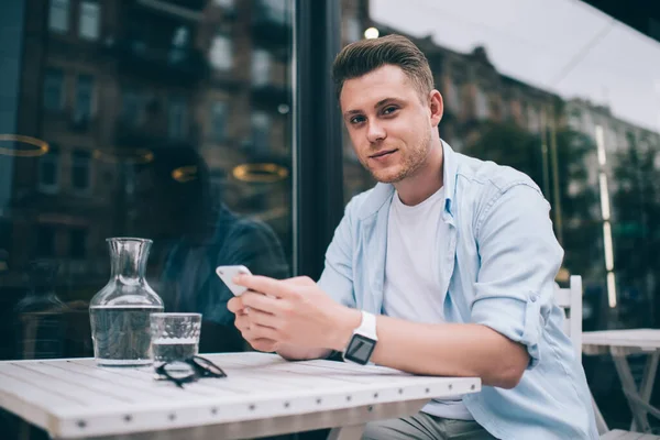 Young Millennial Man Casual Clothes Sitting Table Terrace Holding Smartphone – stockfoto