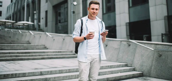 Handsome Millennial Man Holding Cup Coffee Smartphone While Standing Modern — Stock Photo, Image