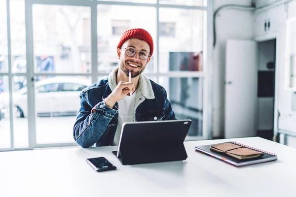 Junge Lächelnde Bärtige Freiberufler Mit Brille Und Warmer Kleidung Sitzen — Stockfoto