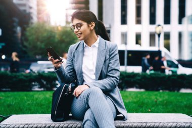 Resmi olarak başarılı olan kadın girişimci, cep telefonu aygıtı ile veri kontrolü yaparken, yönetici iş kadını gülümserken cep telefonu uygulaması ile gönderilmesi için e-posta iletisi yazıyor.