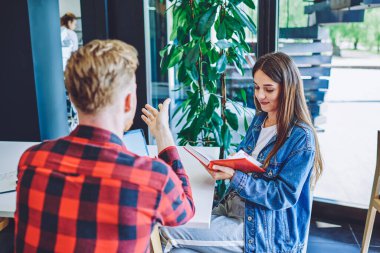 Kafkasyalı zeki erkek ve kadın öğrenciler üniversite için ödev yapıyor proje için bilgi arıyorlar, akıllı adam ve kadın birlikte ders kitabı seyahatini planlarken fikirleri tartışıyorlar.