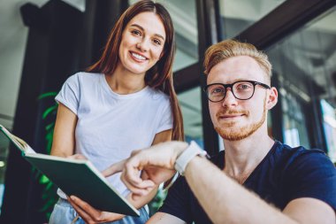 Başarılı gülümseyen erkek ve kadın blogcuların iş birliği sırasında kameraya bakıp yeni yayın için fikirler üretmelerinin portresi, gözlüklü olumlu hipster adamın arkadaşıyla zaman geçirmesi