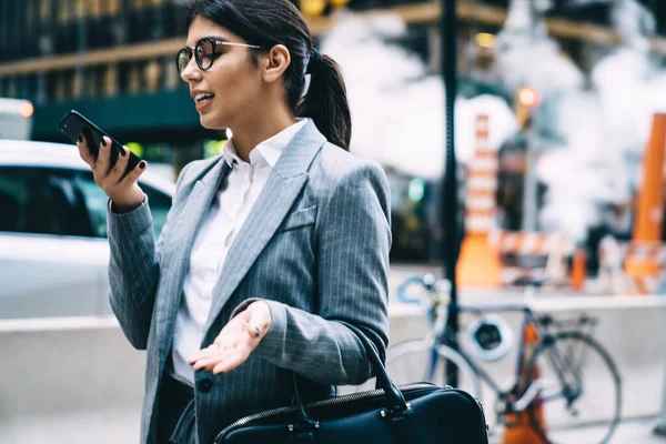 精明的女企业家 站在金融区的城市环境中 戴着光学眼镜 通过智能手机应用程序提供眼睛保护录音信息的严肃女性 — 图库照片