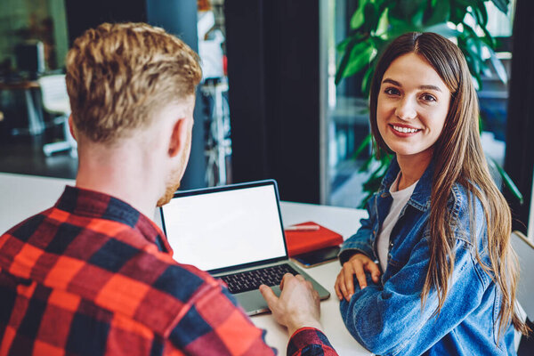 Портрет счастливой улыбающейся женщины-фрилансера, сотрудничающей с другом-мужчиной с помощью бесплатного беспроводного доступа в Интернет на ноутбуке с пустым экраном для рекламного текста или Вашей веб-страницы

