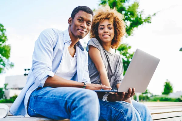 穿着休闲装的非洲裔美国青年男女的画像 穿着休闲装 在镜头前微笑着坐在城市的环境中 手持笔记本电脑 — 图库照片