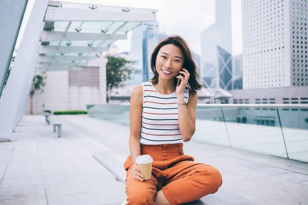 成功したアジアの女性の肖像は コーヒーを飲みながら 街の通りで休むための無料の時間の間にカメラで笑顔 幸せな中国の観光客は 携帯電話ローミング接続を介して呼び出します — ストック写真