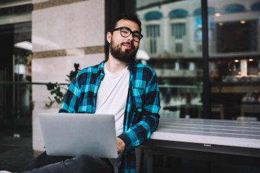 Görme korumalı gözlüklü Asyalı olumlu bir erkek bilgisayar başında bekliyor, yetenekli yenilikçi adam programlıyor uzaktan kumandalı işi ve teknolojisi var ve 4G kullanıyor.