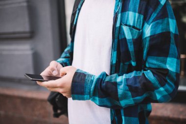 Modern akıllı telefonu elinde tutan bir adamın sokak kurulum uygulaması üzerinde durduğu, sosyal ağlarda cep telefonuna bağlı cep telefonuyla mesajlaşan bir adamın el yazısı. 