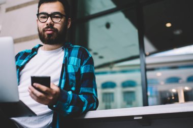 Bluetooth ve uygulamalarla akıllı telefonu bilgisayarına bağlayan gözlüklü Asyalı sakallı bir milenyum adamı. Multimedya dosyalarını senkronize etmek için bir uygulama. Cep telefonu kamerasına bakan hippi adam.