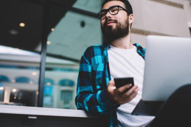 Asyalı sakallı hippi adam cep telefonu tutuyor, para kazanıyor. Piyasada alışveriş yapıyor. Bin yıllık gözlüklü adam dışarıda iş için dizüstü bilgisayar ve akıllı telefon kullanıyor.