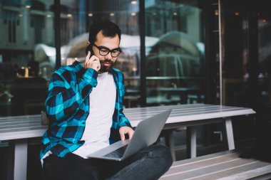 Genç Asyalı erkek serbest çalışan servis operatörüyle cep telefonu görüşmesi yapıyor. Hipster adam cep telefonuyla online alışveriş yaptığını doğruladı.