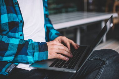 Bir insanın dizüstü bilgisayarında yazarken çekilmiş görüntüsü 4G internet bağlantısı üzerinden çalışıyor, genç erkek klavye için dijital cihaz ağı kullanıyor ve uzaktan geliştirme yapıyor.