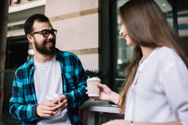Neşeli, kaygısız hippi çift kafede eğleniyor, konuşuyor ve şakalaşıyor, mutlu çok ırklı erkek ve kadın meslektaşlar kahve molası veriyor, ellerinde yemek fincanları tutuyor ve gülüyorlar. 