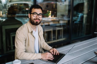 Zengin Asyalı erkek portresi. Modern dizüstü bilgisayarda programlama yapıyor. Kafede kablosuz bağlantıyla serbest çalışıyor.