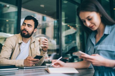 Kahve molası sırasında kafede oturan çok ırklı erkek ve kadın öğrenciler akıllı telefonlar kullanarak iletişimi görmezden geliyorlar. Meslektaşları modern cihazlara bağımlı cep telefonları üzerinde araştırma yapıyorlar.