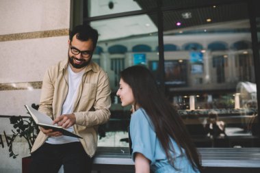 Mutlu Asyalı adam boş sayfaları işaret ederek fikirleri tartışıyor, fikirlerini paylaşıyor, çok ırklı arkadaşlarıyla sohbet ediyor ve Cafeteri 'de boş vakitlerin tadını çıkarıyor.