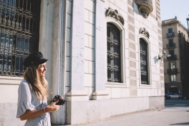 Modern teknolojiye sahip Kafkasyalı pozitif hippi kız. Gösteri yerlerinin fotoğraflarını çekiyor. Başka tarafa bakıyor ve gülümsüyor, gündelik giysiler giymiş mutlu bir kadın.