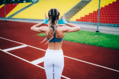 Kaslı ve güçlü bir kadının stadyumda dikilip kauçuk kurdeleyle antreman yaptığı arka plan.