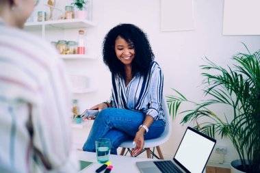 Hoş bir gülümsemesi olan Afro-Amerikalı kadın elinde telefonla iş görüşmesinde mahsul işçisiyle sohbet ederken dizüstü bilgisayarını aldı. 