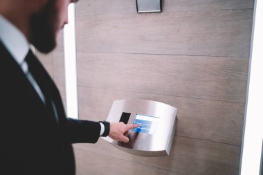 Modern ofisteki modern dijital dokunmatik ekranı kullanarak zarif giysiler içindeki yüzü olmayan yetişkin sakallı adamın kırpma tarafı.