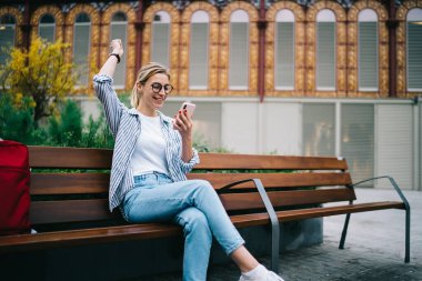 Kot pantolonlu ve gömlekli neşeli genç bir bayan. Gözlüklü. Zaferi kutluyorlar.