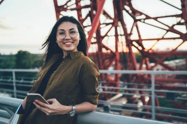 İnternette sörf yaparken kameraya gülümseyen modern akıllı telefon cihazıyla komik Asyalı kadın blog yazarının yarım boy portresi, dijital teknolojili mutlu ergen.