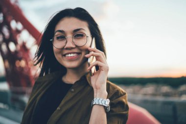 Cep telefonu uygulaması aracılığıyla kameraya gülümseyen şık gözlüklü neşeli Asyalı ergen portresini yakından çek. Gözlüklü mutlu kadın teknolojiyle telefon ediyor.