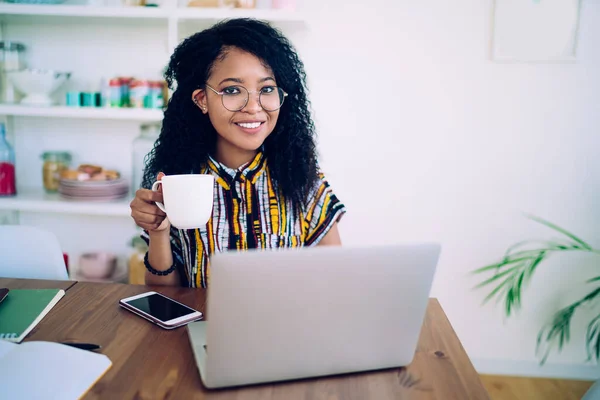 Glada Etniska Kvinna Glasögon Bläddra Bärbar Dator Och Dricka Kaffe — Stockfoto