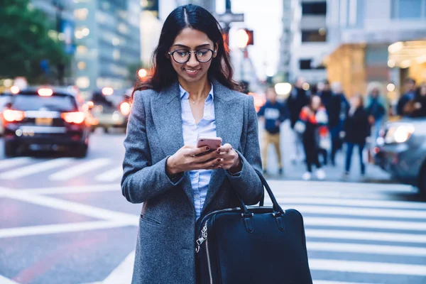 Vonzó Etnikai Üzletasszony Szemüvegben Szürke Kabátban Mosolyogva Nézi Mobiltelefont Miközben — Stock Fotó