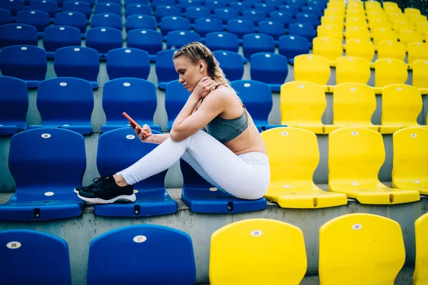 Spor Ayakkabılı Spor Kıyafetli Stadyum Koltuklarında Oturmuş Internette Turuncu Akıllı — Stok fotoğraf