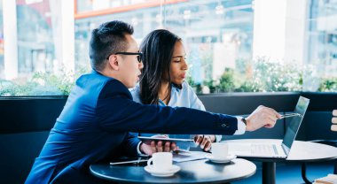Kafe 'de, masada oturan, yeni iş projesinde birlikte çalışırken dizüstü bilgisayarı işaret eden, Afro-Amerikan bir adamla modern zarif bir adam.